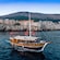 A wooden boat sails past the ramparts of a medieval city in Dubrovnik, Croatia